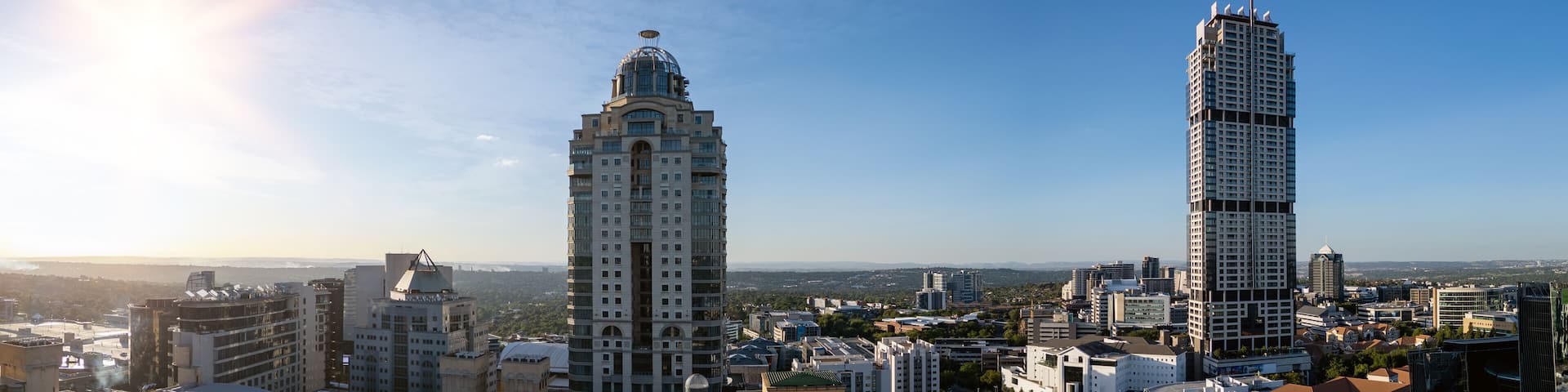 Two prominent skyscrapers, a dome-topped building, and a dense urban landscape with a clear sky.
