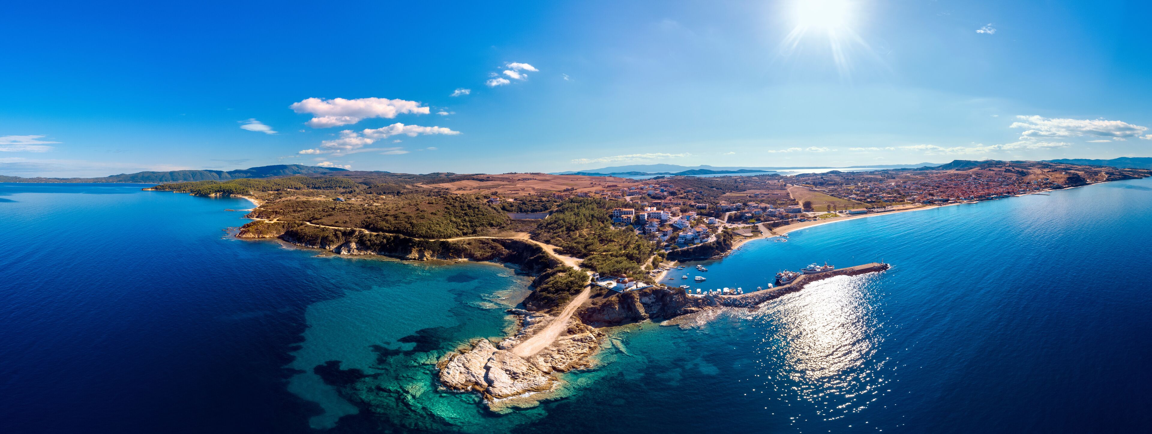 Church and sea with beach and mountains in Nea Roda