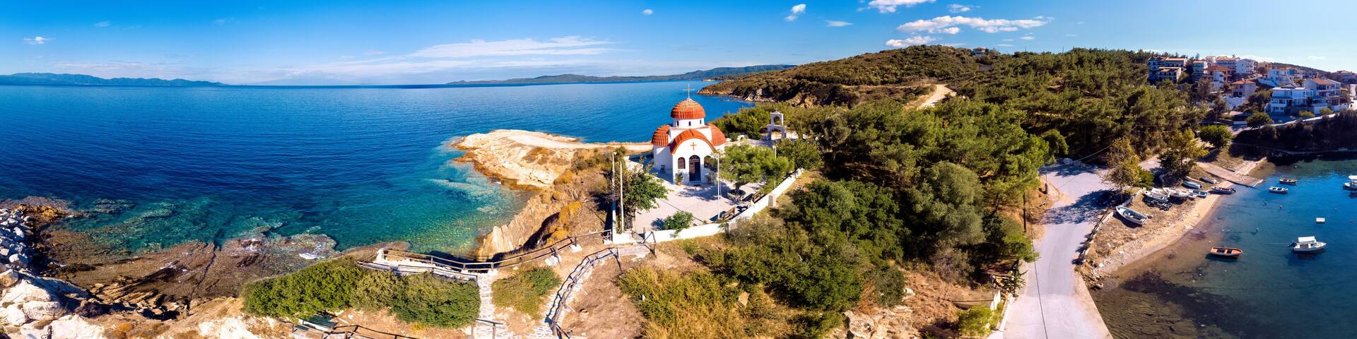 Church and sea with beach and mountains in Nea Roda