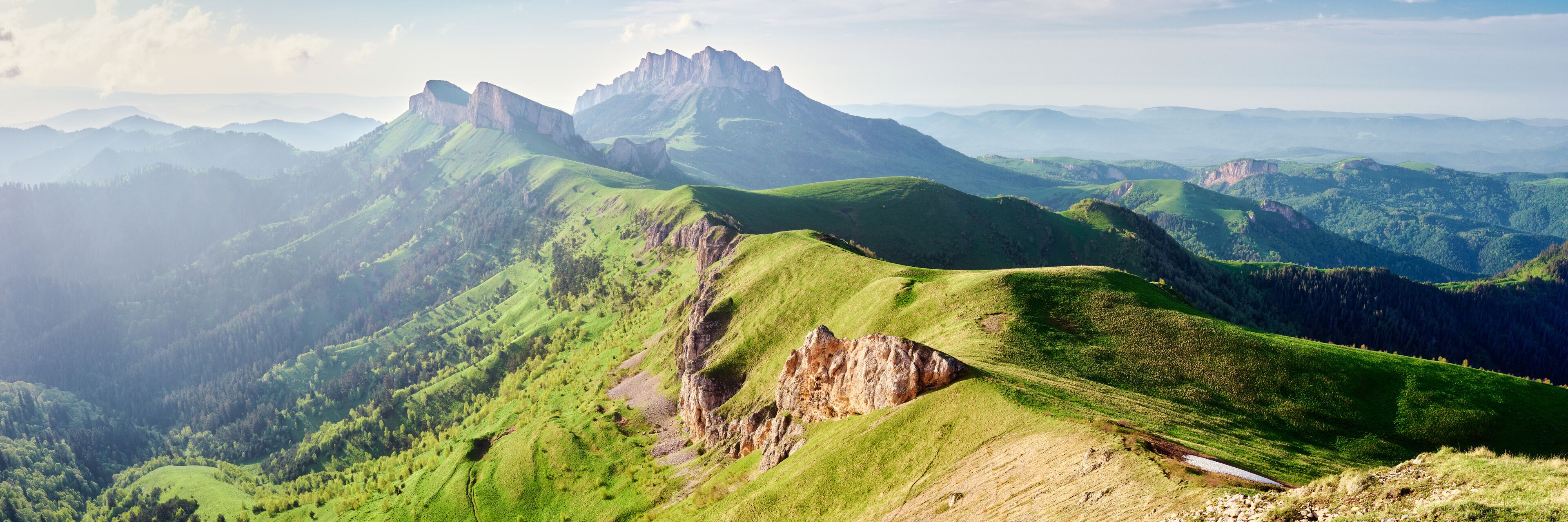 A mountainous landscape with green hills and rocky outcrops.