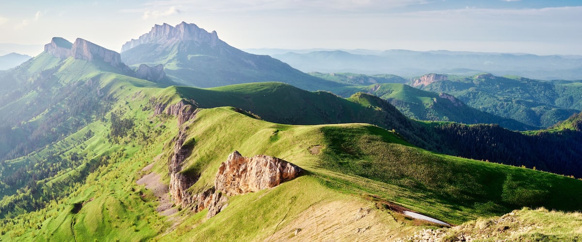 A mountainous landscape with green hills and rocky outcrops.
