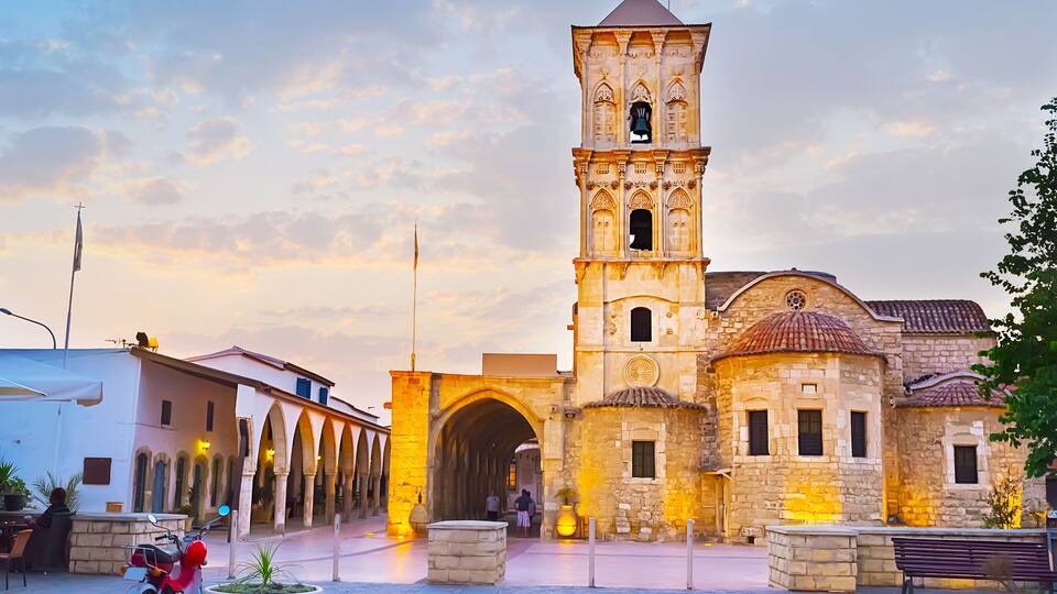 A historic building with a bell tower, arches, and a courtyard.