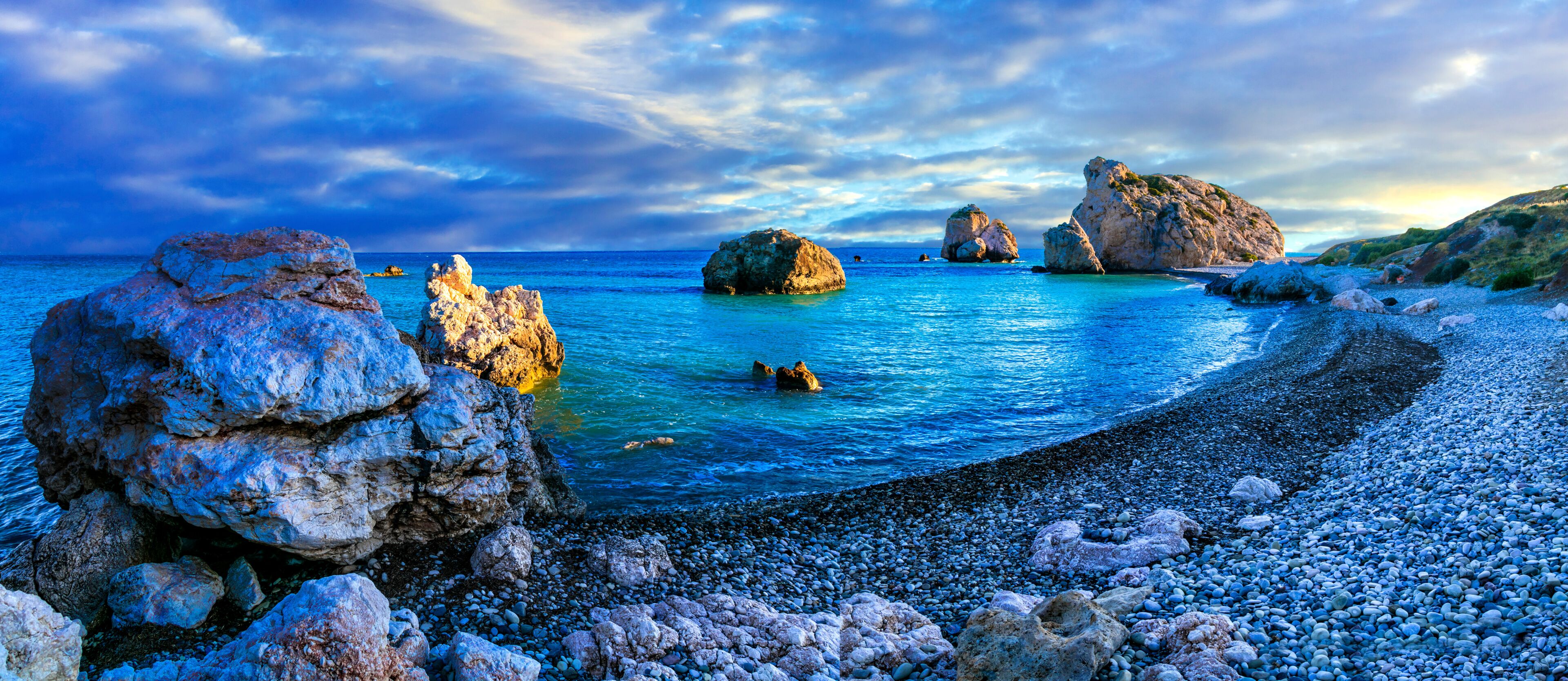 Una costa rocosa con aguas azul turquesa y grandes rocas.