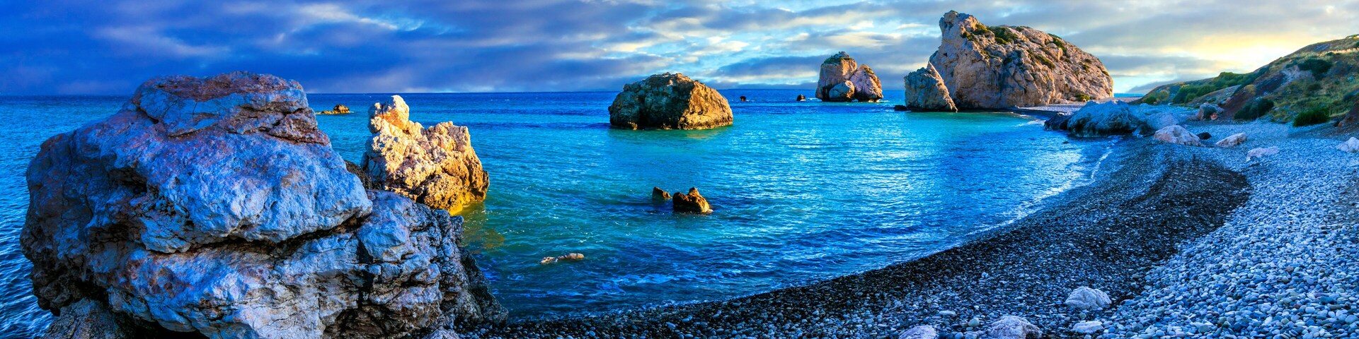 Una costa rocosa con aguas azul turquesa y grandes rocas.