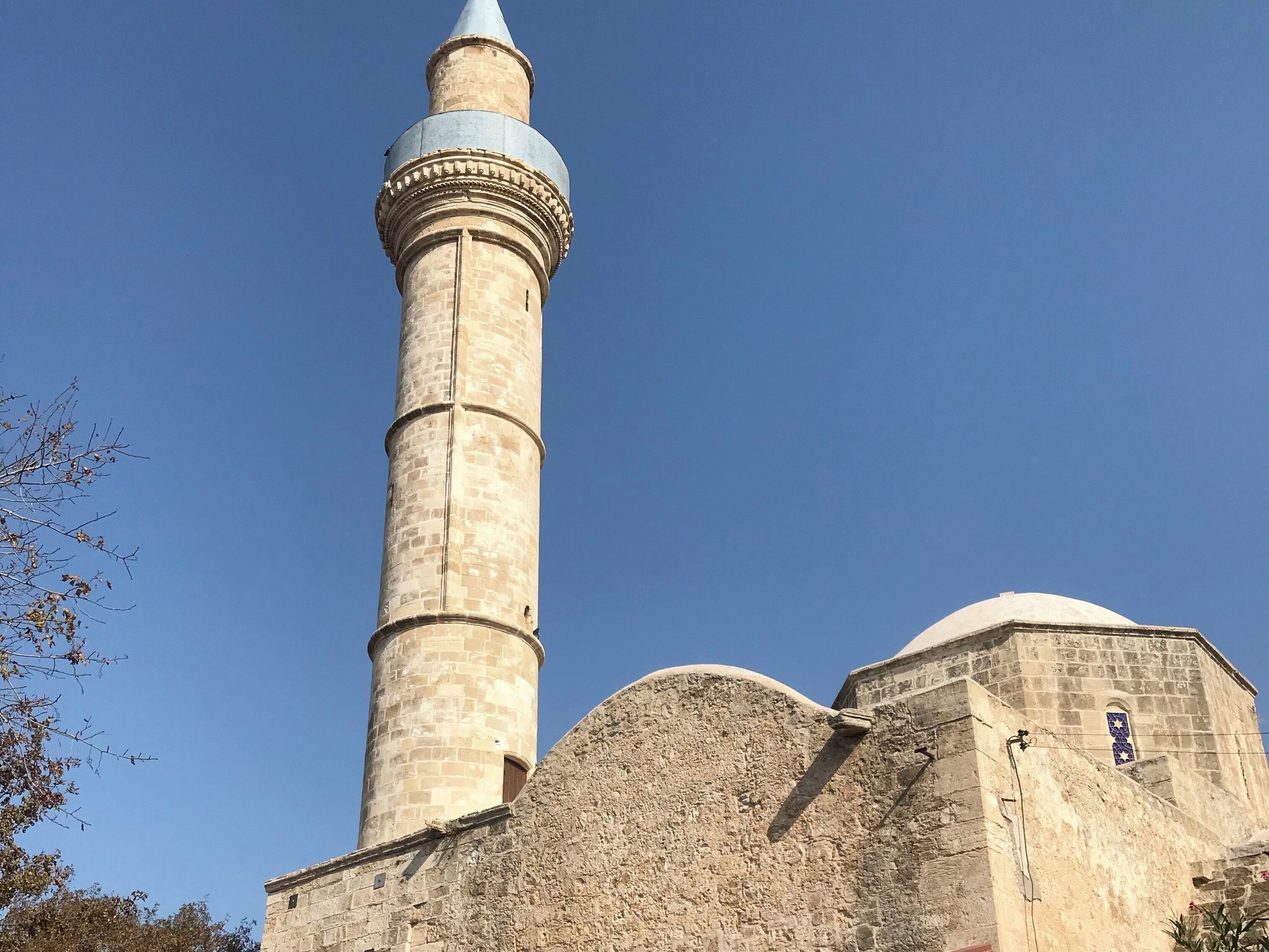 A tall stone minaret with a dome and a smaller adjacent building.