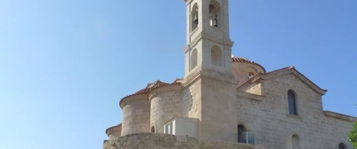 A historic stone building with a bell tower, a no-entry sign, and a parked car.