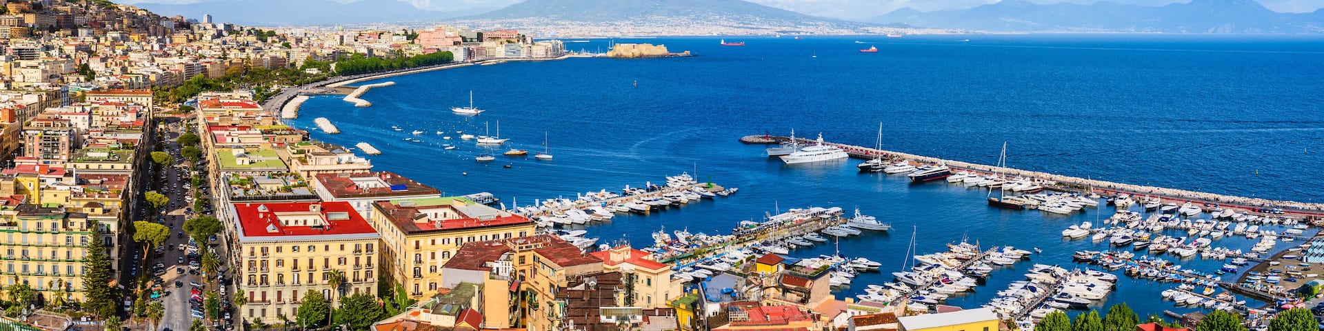 Naples city and port with Mount Vesuvius on the horizon seen from the hills of Posilipo. Seaside landscape of the city harbor and golf on the Tyrrhenian Sea