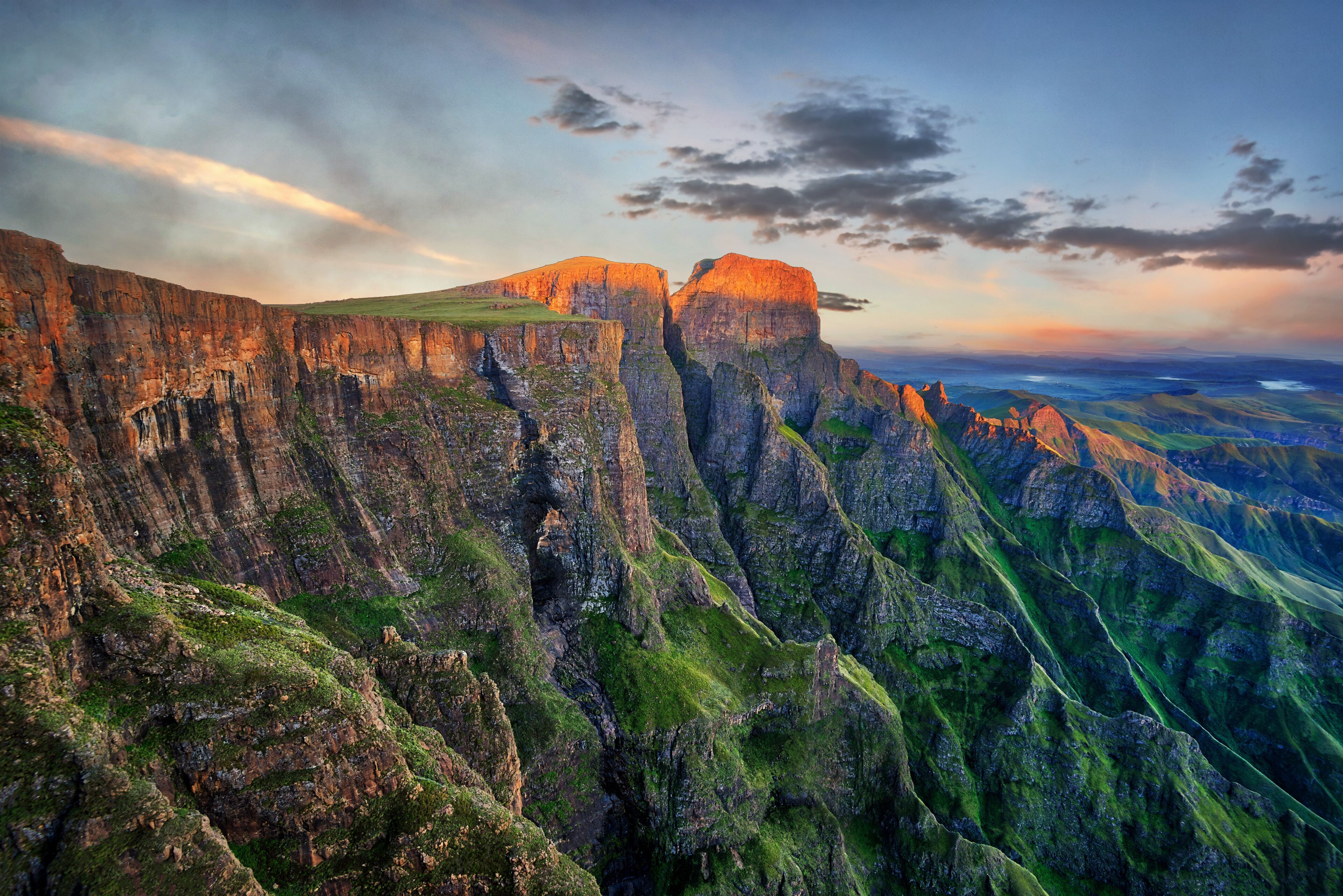 A rugged mountain range with steep cliffs and lush green vegetation.