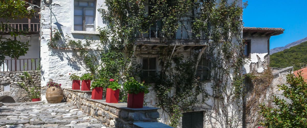 A white building with red planters and vines on the facade.