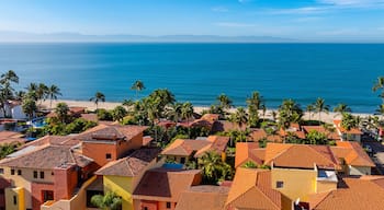 A coastal town with terracotta-roofed buildings, palm trees, and a beach.