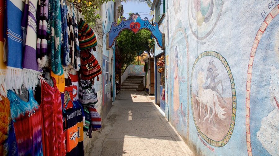 Un estrecho callejón con textiles y murales coloridos, que conduce a una escalera.