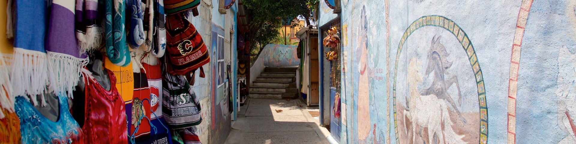 Un estrecho callejón con textiles y murales coloridos, que conduce a una escalera.