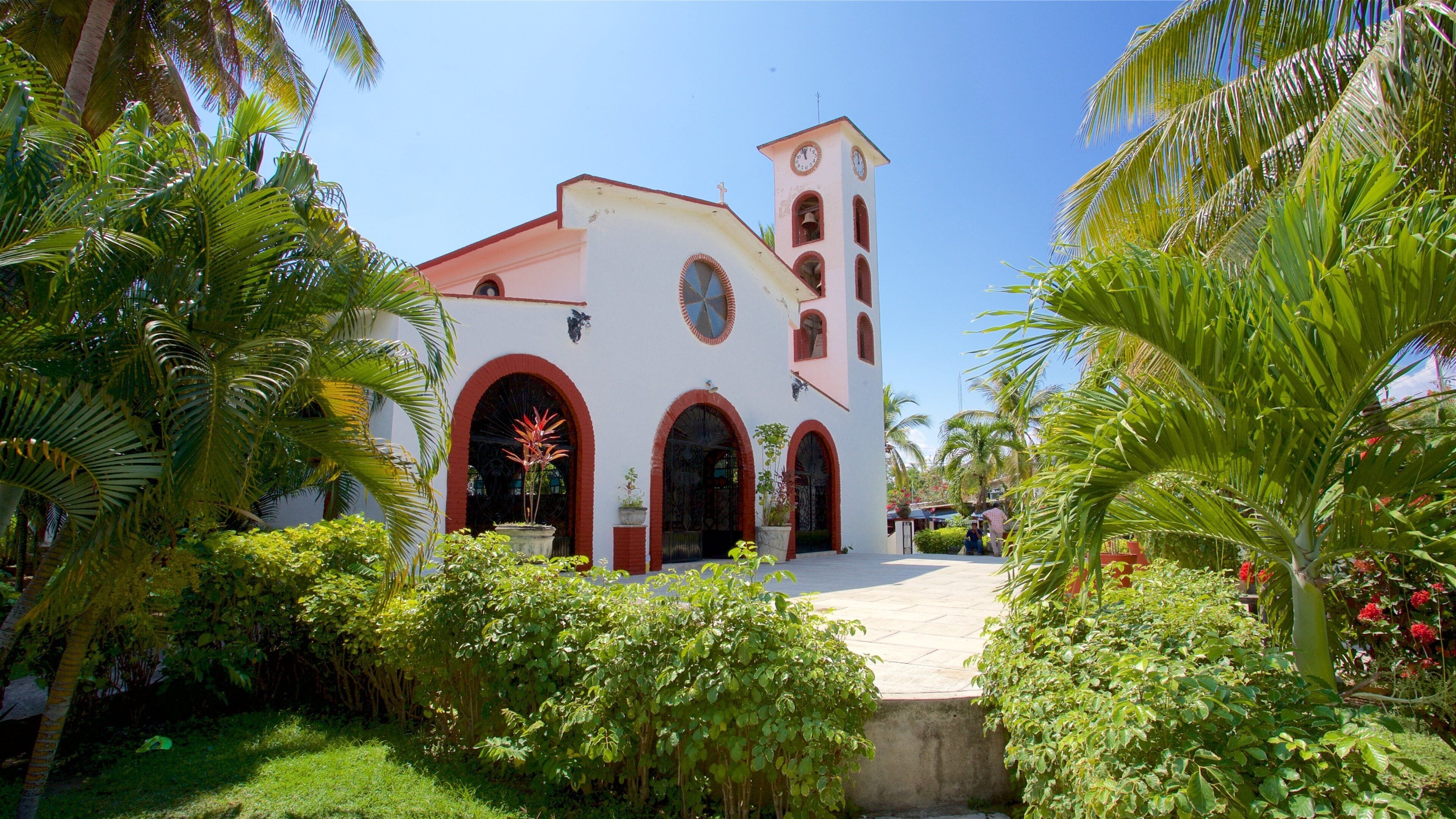 A church with a red-tiled roof, arched doorways, and a bell tower.