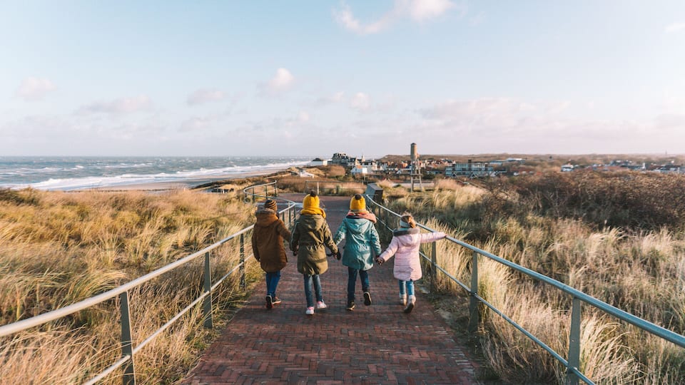 A pathway leading to a coastal area with grassy dunes and a view of the sea.