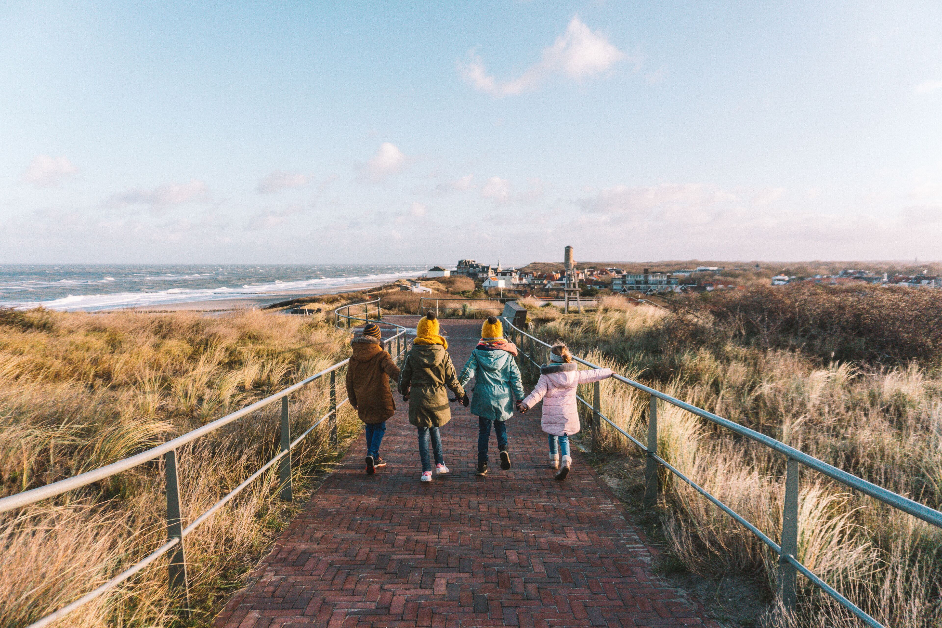 A pathway leading to a coastal area with grassy dunes and a view of the sea.
