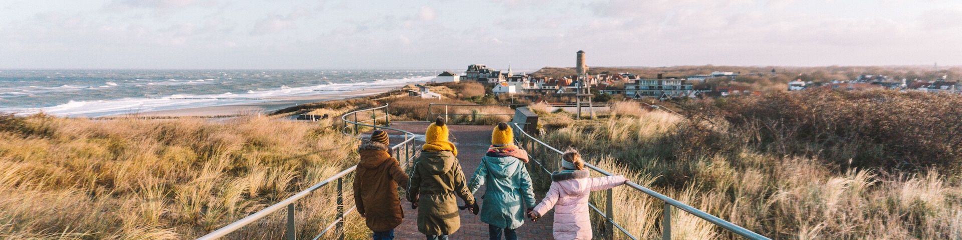 A pathway leading to a coastal area with grassy dunes and a view of the sea.