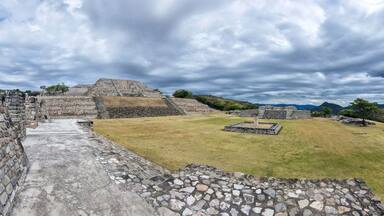 Ancient stone ruins with a large pyramid and a stepped structure.