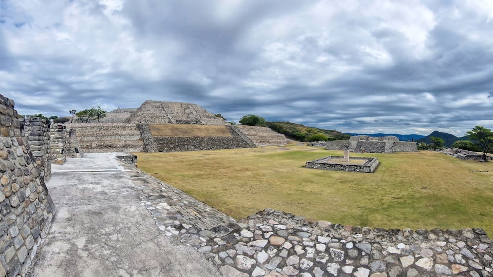 Ancient stone ruins with a large pyramid and a stepped structure.