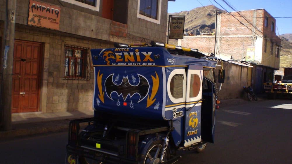 A blue motorcycle with a bat design and 'Penix' branding parked on a street.
