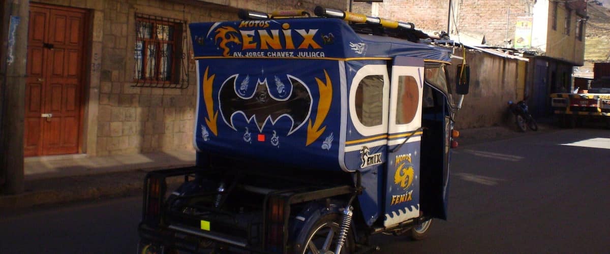 A blue motorcycle with a bat design and 'Penix' branding parked on a street.
