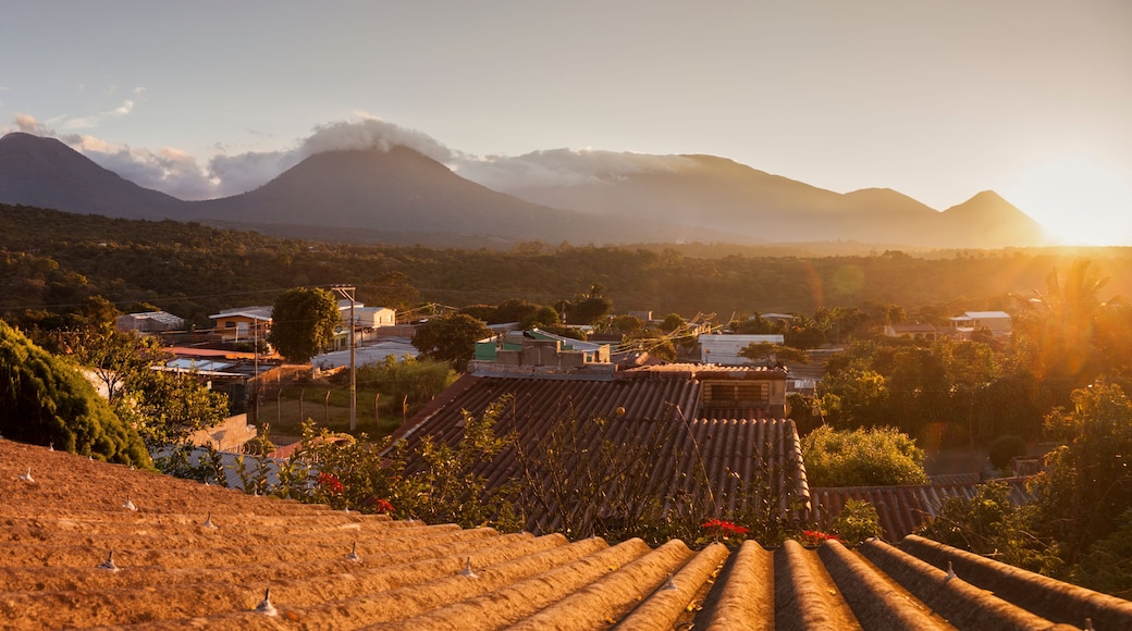Paisagem rural com campos em socalcos, uma aldeia e montanhas ao fundo.