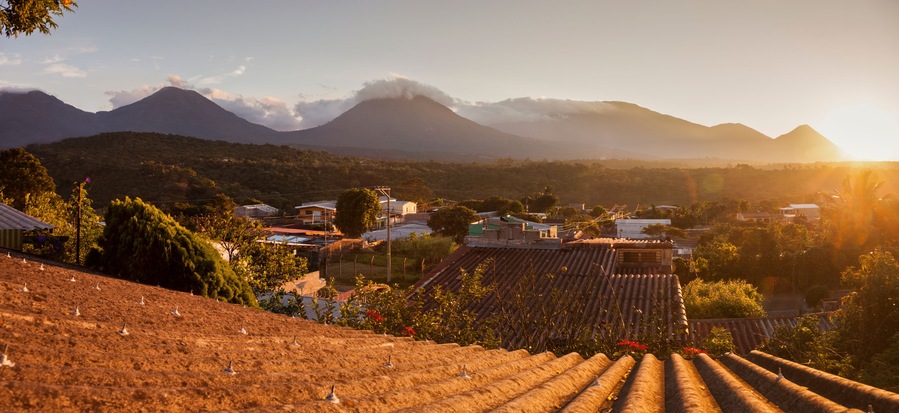 Paisaje rural con campos en terrazas, un pueblo y montañas al fondo.