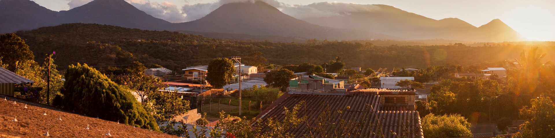 Paisaje rural con campos en terrazas, un pueblo y montañas al fondo.