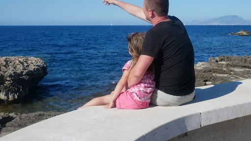 Father with his little daughter sitting on a sea cost (Favignana, Sicily, Italy).