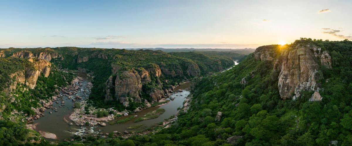 A river winding through a canyon with steep cliffs and dense greenery.