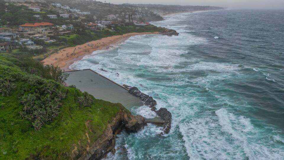 A coastal town with a beach, rocky shoreline, and a sea wall.