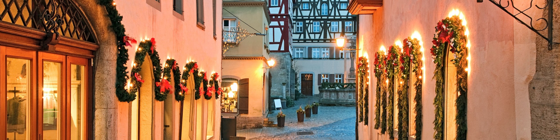 Rua de paralelepípedos ladeada por edifícios decorados com enfeites natalinos.