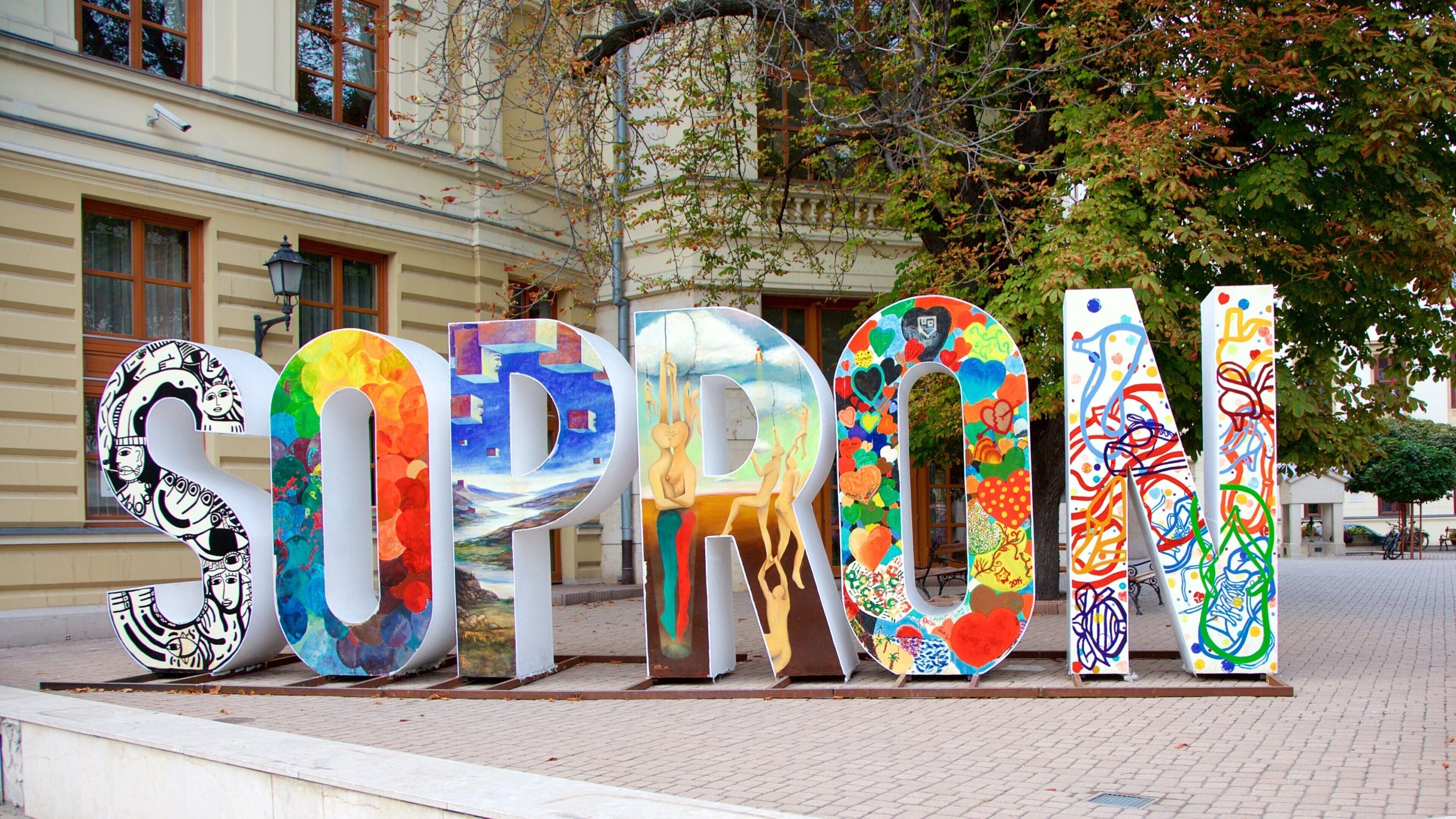 Grandes letras coloridas que deletrean 'SOPRON' sobre una superficie pavimentada.