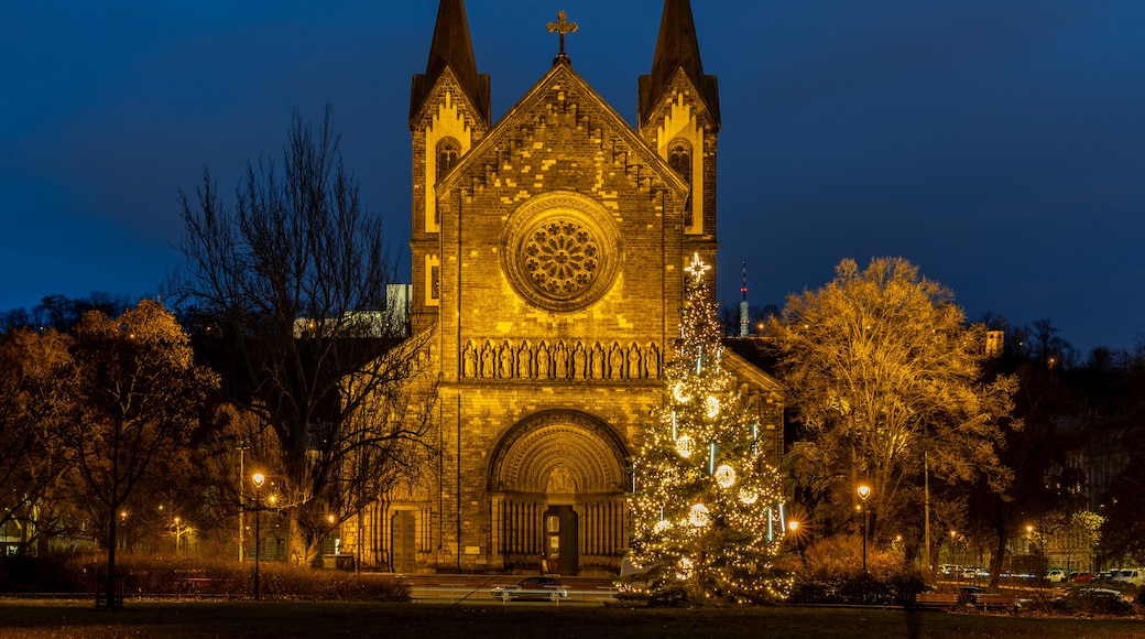A Gothic-style church with two spires, a large rose window, and a Christmas tree in front.