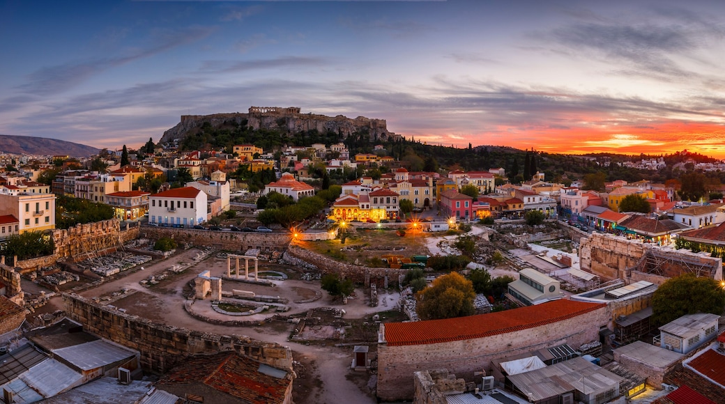 A historic town with ancient ruins, a prominent castle on a hill, and a sunset sky.