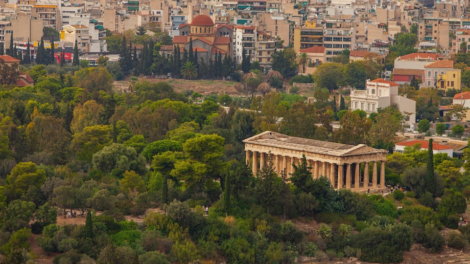 Paisagem urbana com um templo grego antigo imponente, cercado por vegetação densa.
