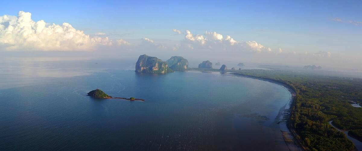 A coastal landscape with a large body of water, several islands, and a dense green area along the shore.