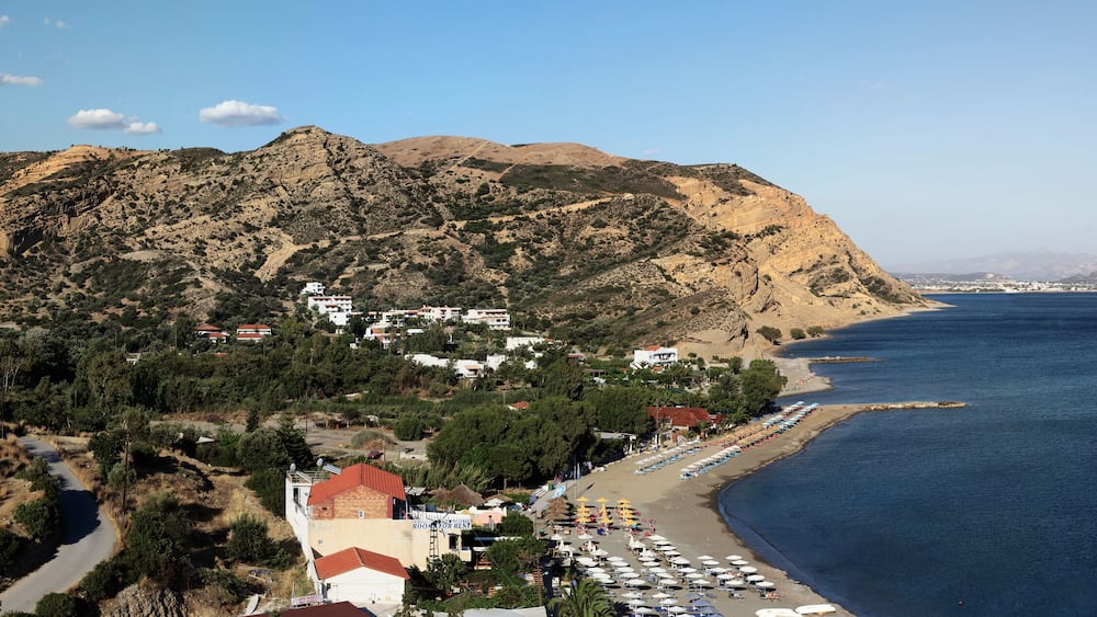Une ville côtière dotée d’une plage, de montagnes et d’un ciel dégagé.