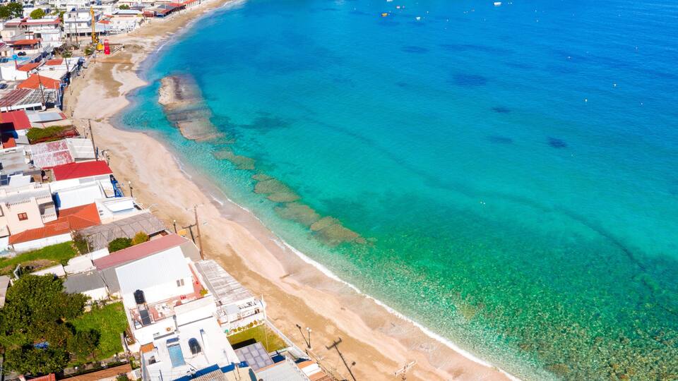 A coastal town with a clear blue sea, sandy beaches, and residential buildings.