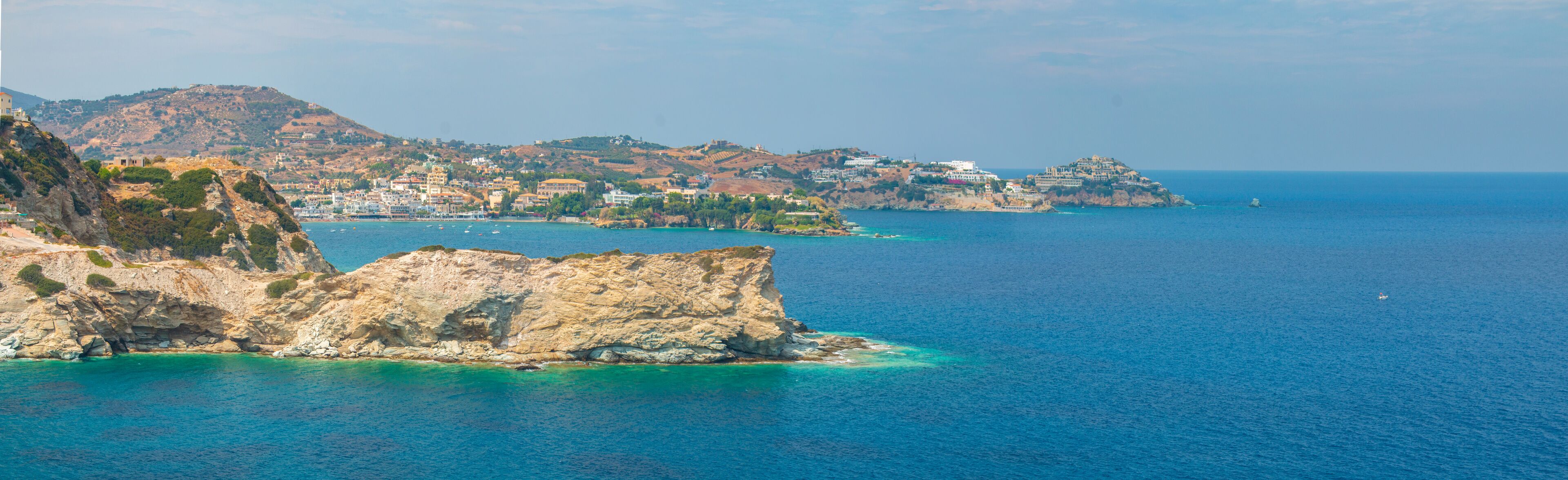 A coastal town with rocky cliffs and a clear blue sea.