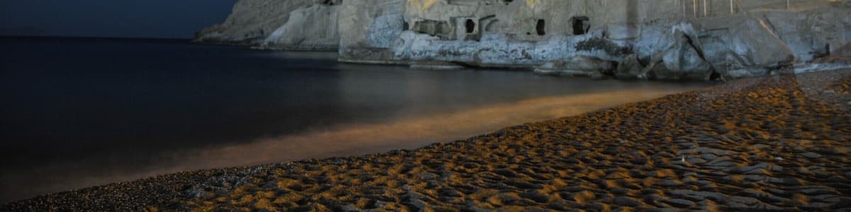 Une côte rocheuse bordée de falaises blanches et de grottes illuminées par des lumières artificielles la nuit.