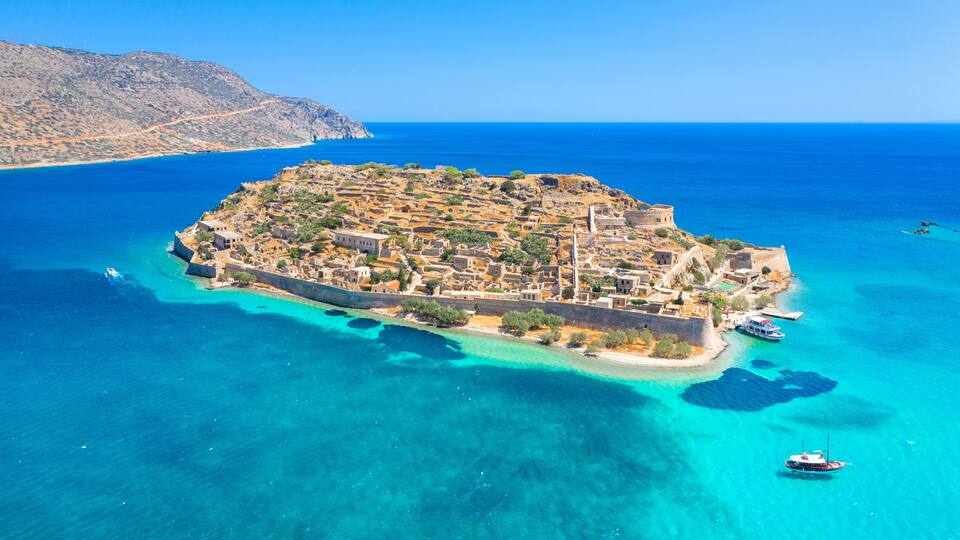 An island with a fortified structure surrounded by clear turquoise waters.