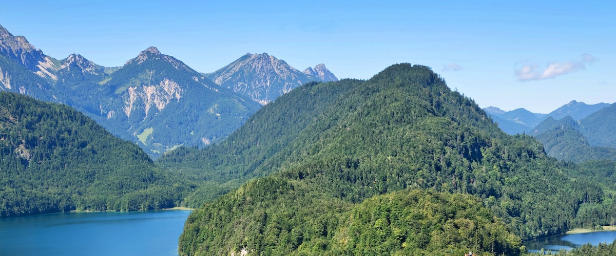 A mountainous landscape with dense forests and a lake.