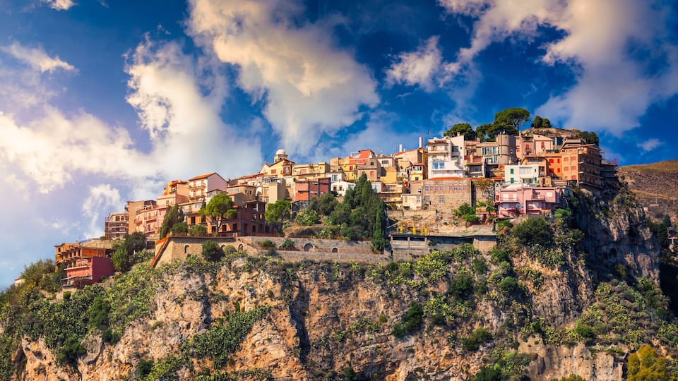 A coastal town built on a cliff with colorful buildings and a clear blue sky.