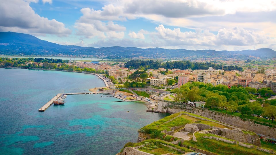 A coastal city with a historic fort, clear turquoise waters, and a mountainous backdrop.