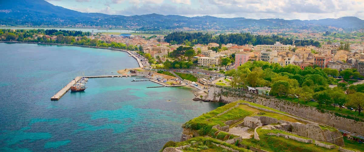 A coastal city with a historic fort, clear turquoise waters, and a mountainous backdrop.