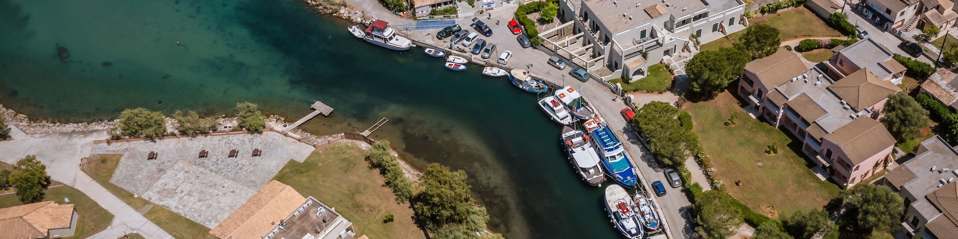 Vista aérea de un pueblo costero con un puerto deportivo, barcos y edificios residenciales.