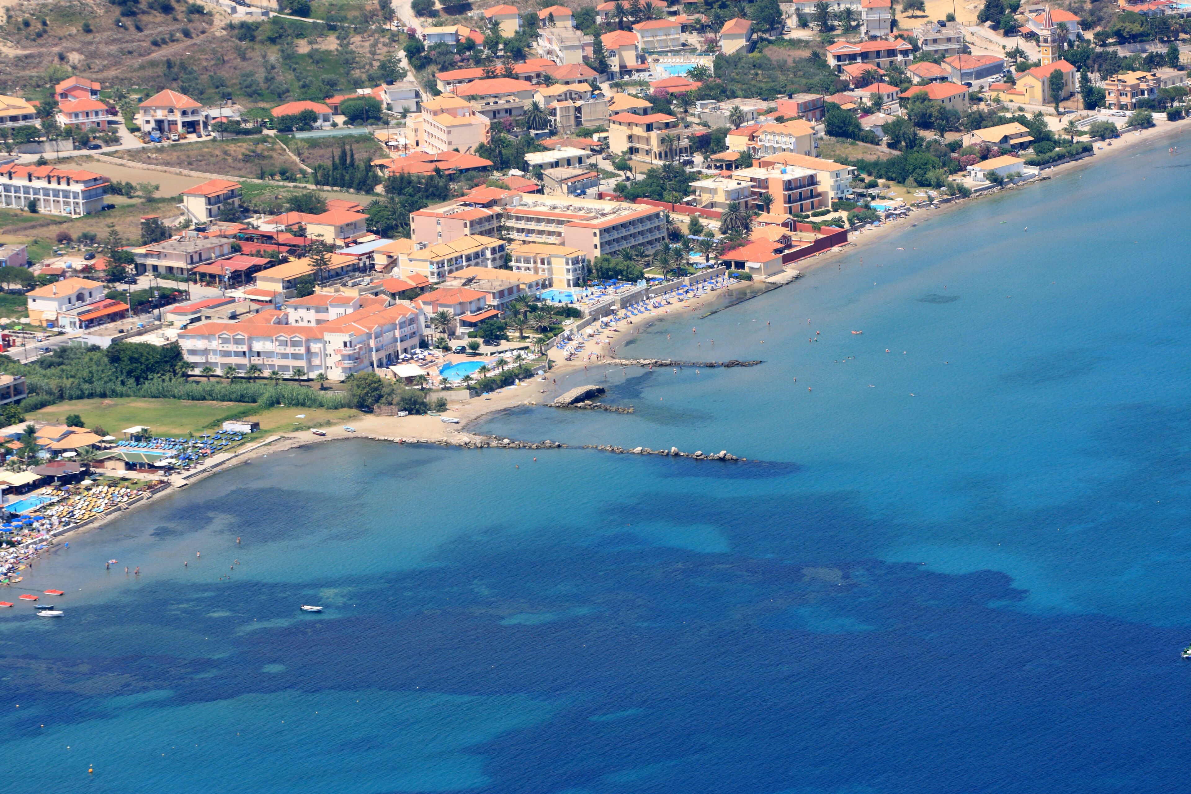 An aerial view of a coastal town with buildings, a beach, and a pier.