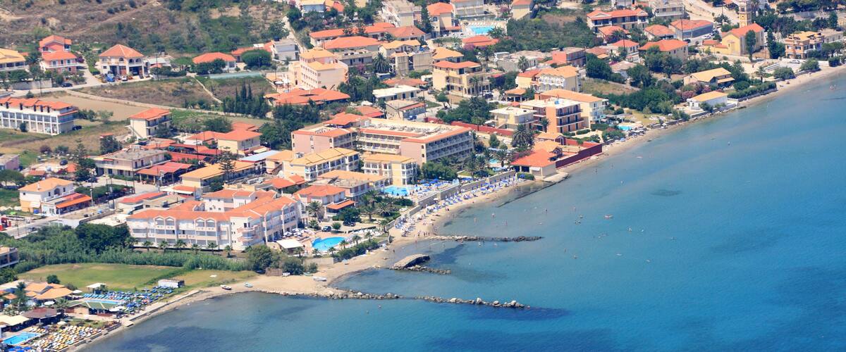 An aerial view of a coastal town with buildings, a beach, and a pier.