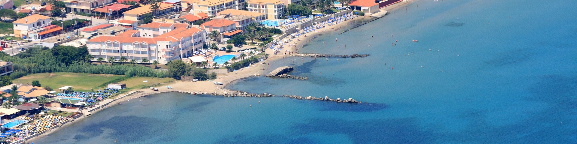 An aerial view of a coastal town with buildings, a beach, and a pier.