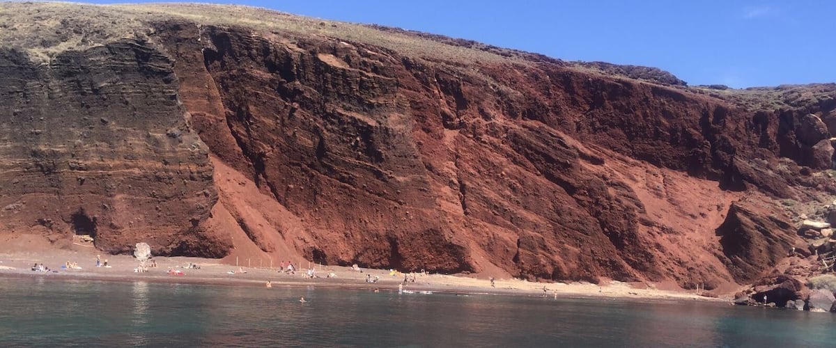 Un paisaje costero con aguas azul turquesa, acantilados rocosos y una playa arenosa.